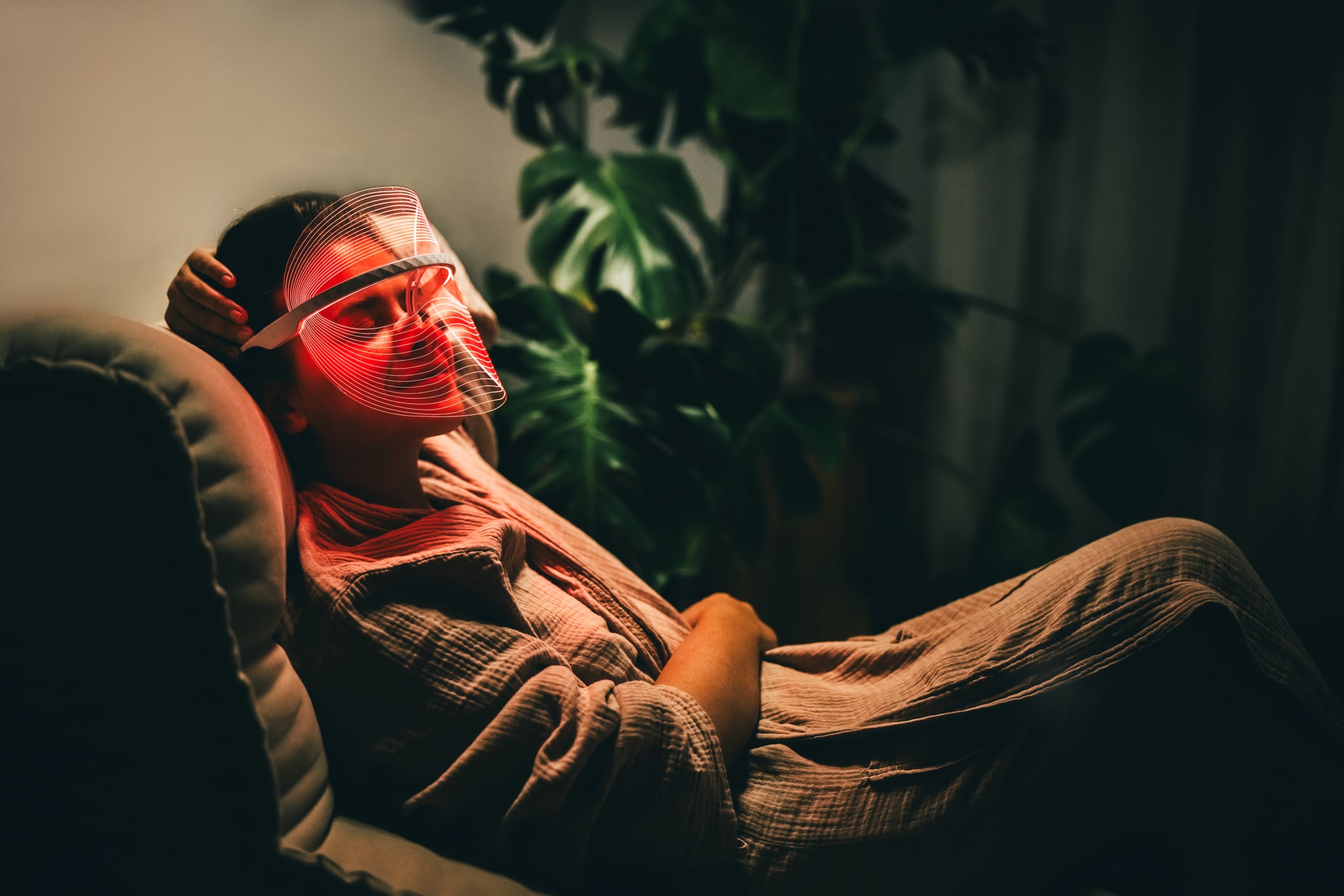 Home relaxation with LED light therapy mask in comfortable indoor domestic setting