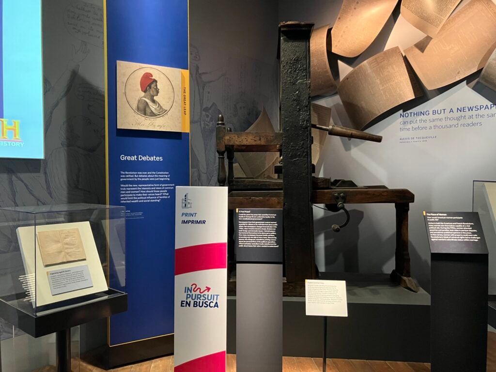 Ben Franklin's old printing press, surrounded by signage.
