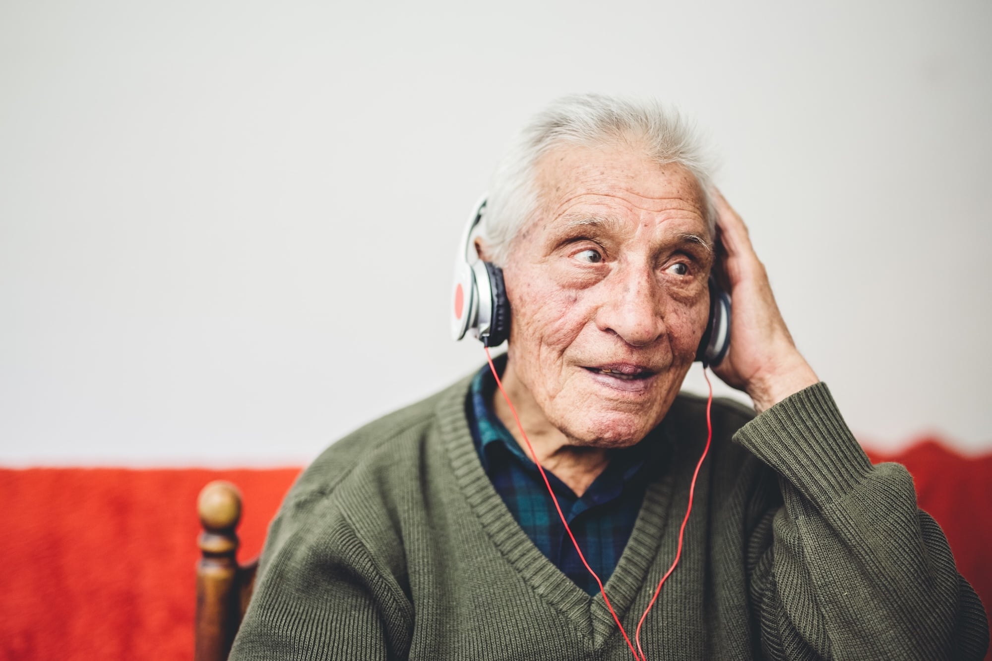 An old man in his 80s listening to his music on a new headset