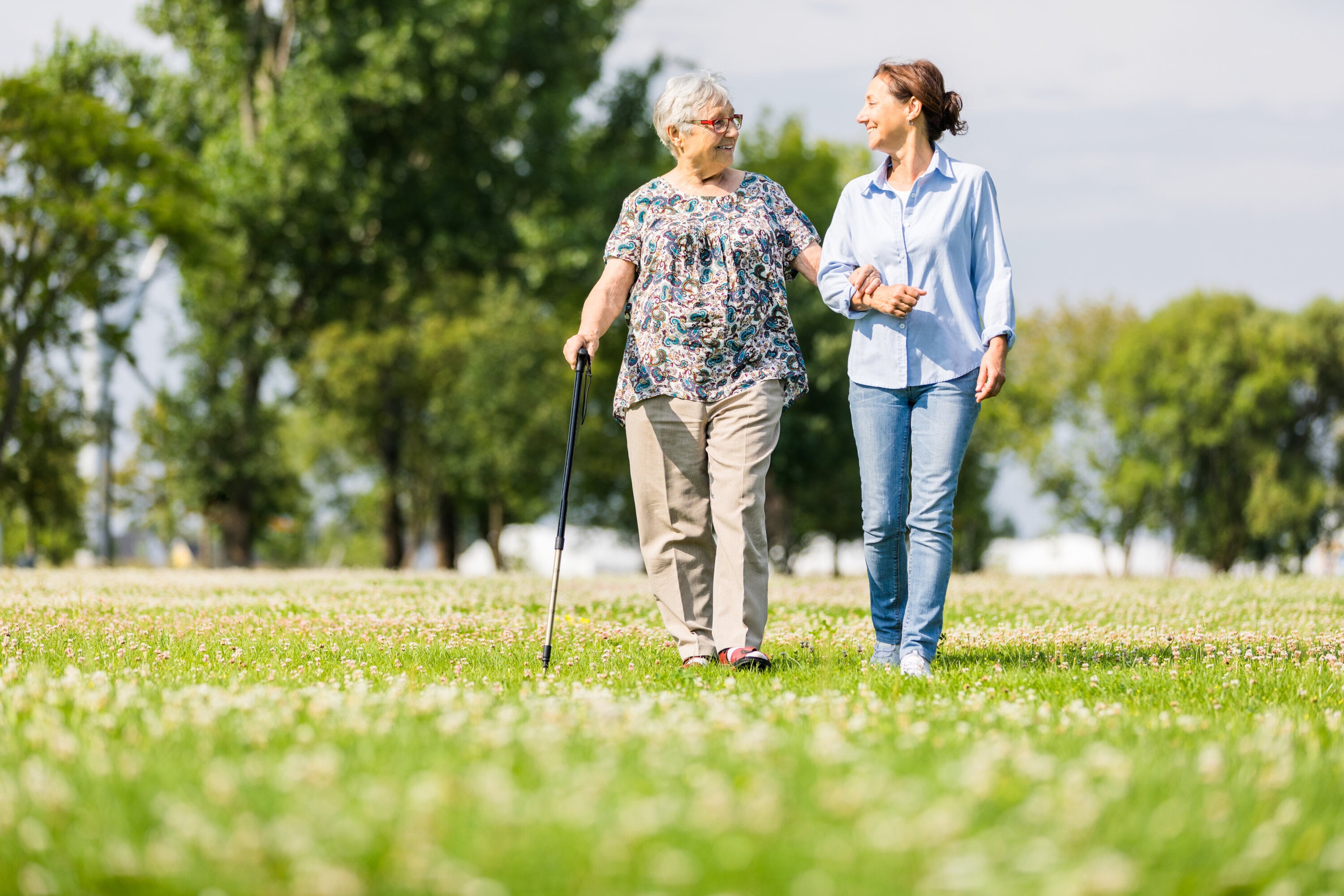Happy senior woman and caregiver walking outdoors - Washingtonian Happy senior woman and caregiver walking outdoors